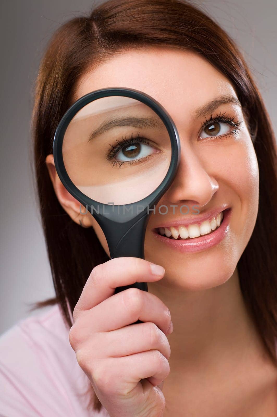 Young business woman looking through loupe close up