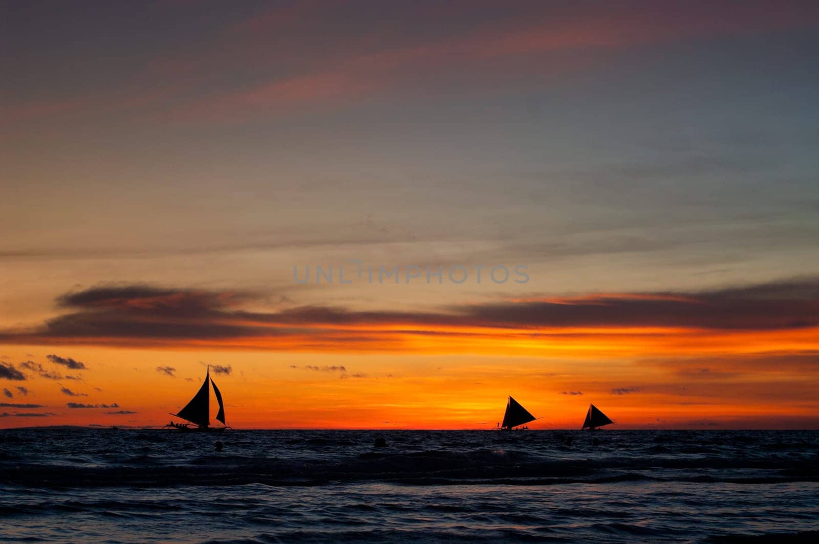 tropical beach with sailing boats at sunset