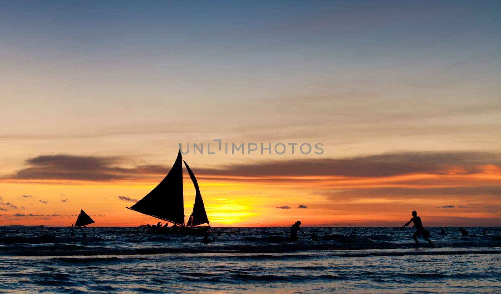 tropical beach with sailing boats at sunset