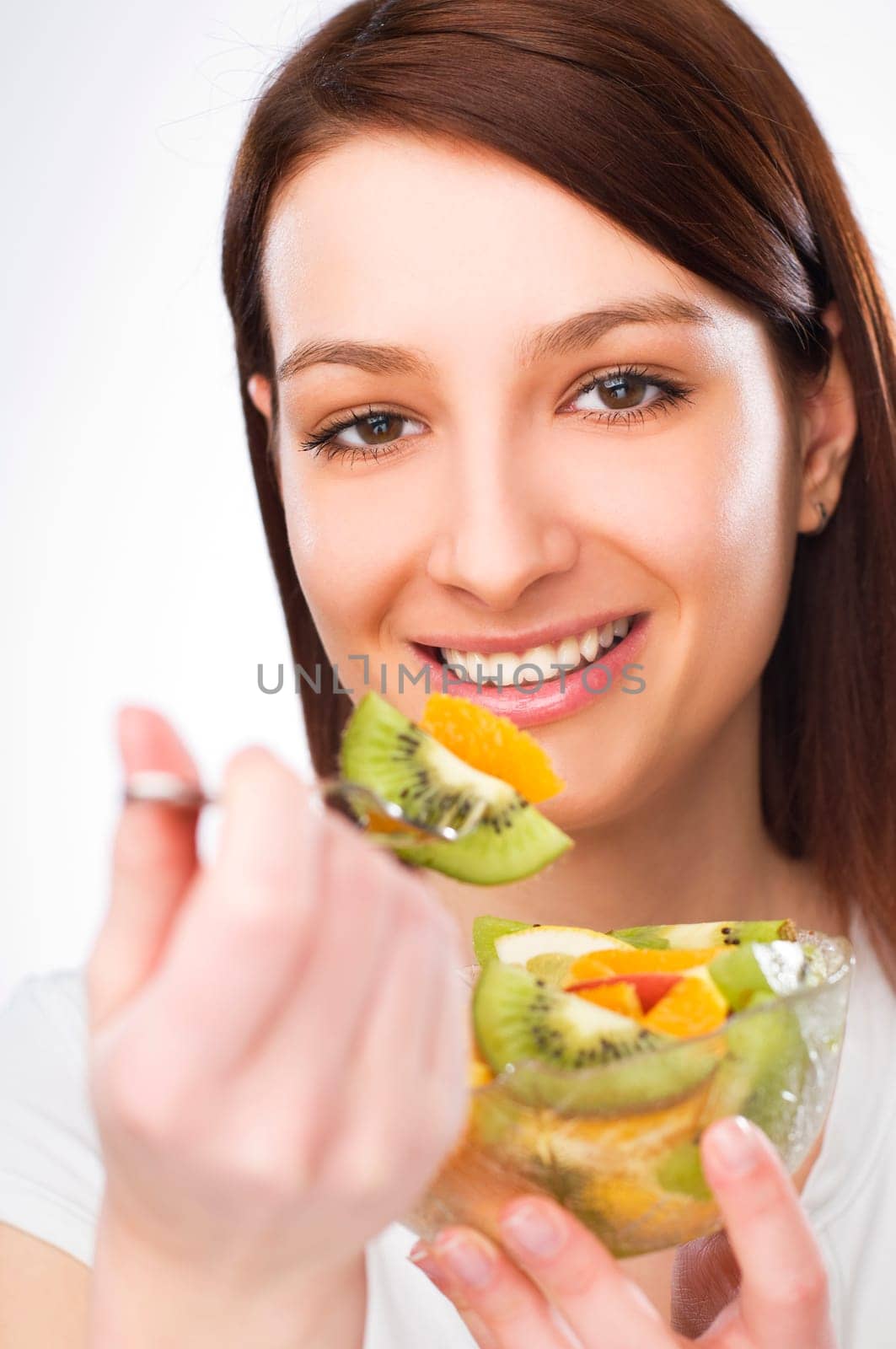 beautiful brunette girl eating fruit salad close up