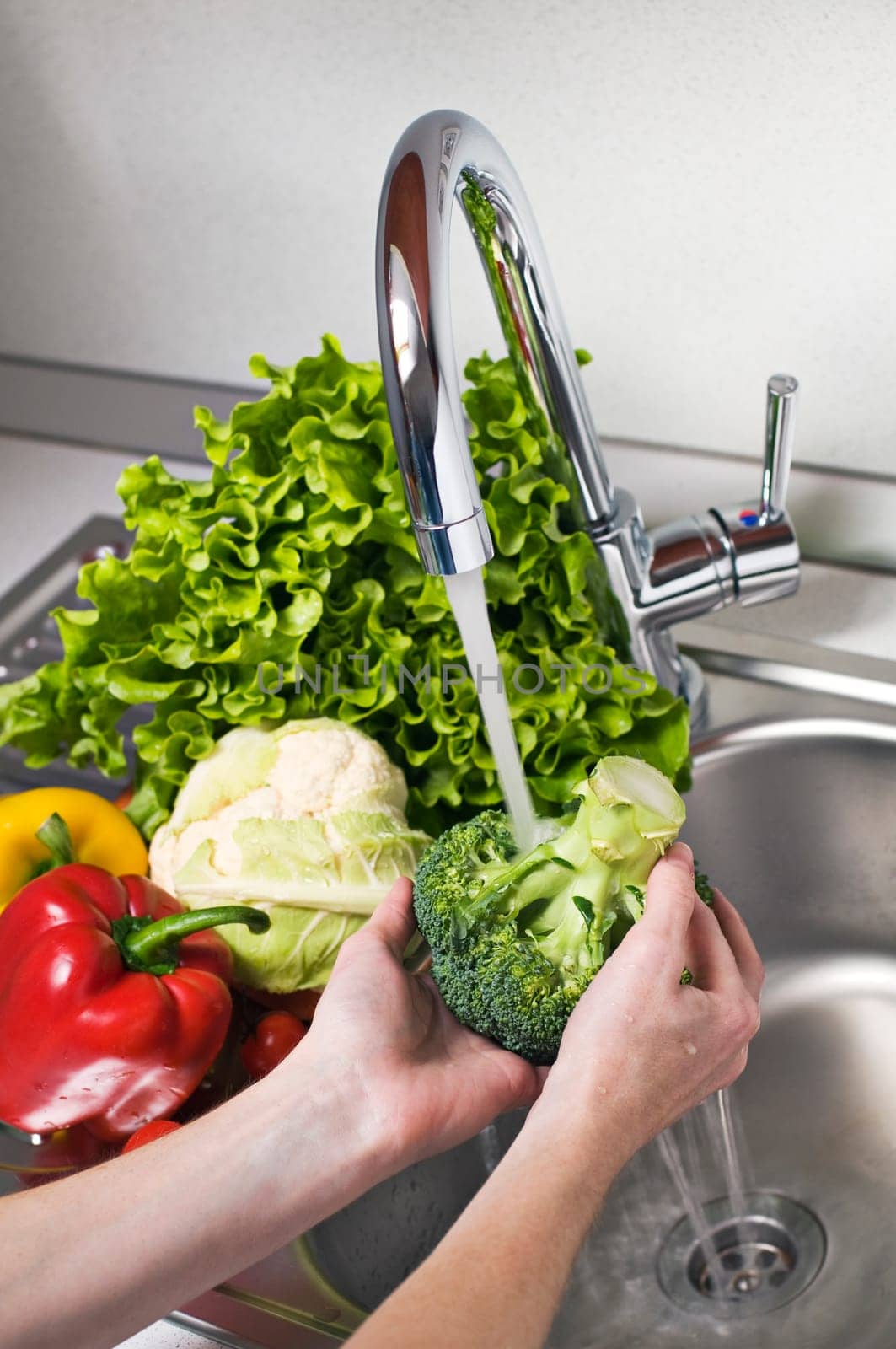 Woman washing vegetables in kitchen close up