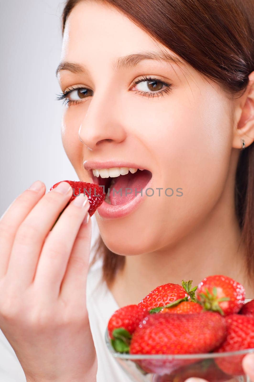 beautiful brunette girl eating a strawberry close up