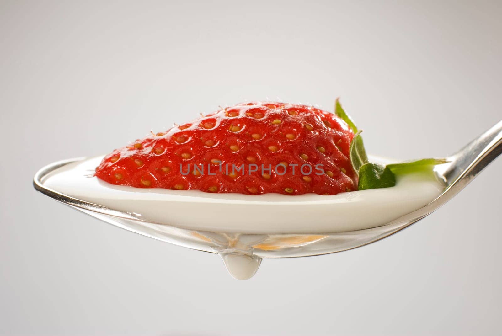 fresh strawberry fruit on a spoon with yogurt close up