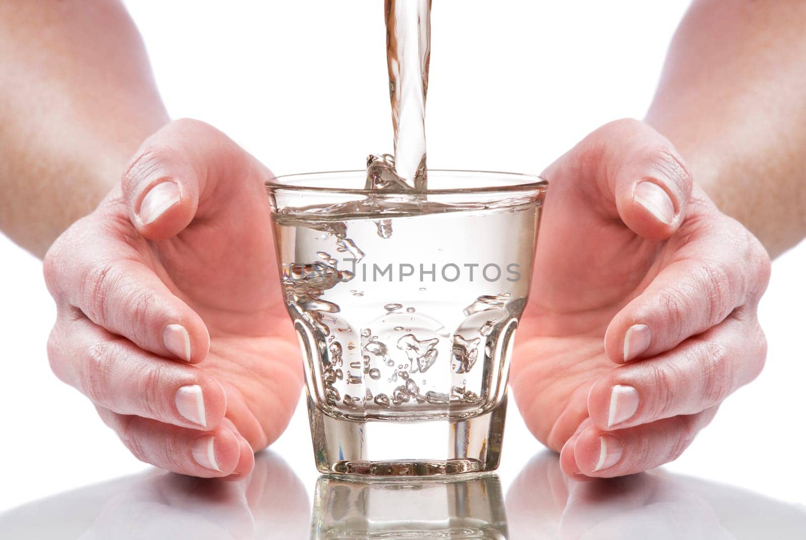glass of fresh water between hands close up
