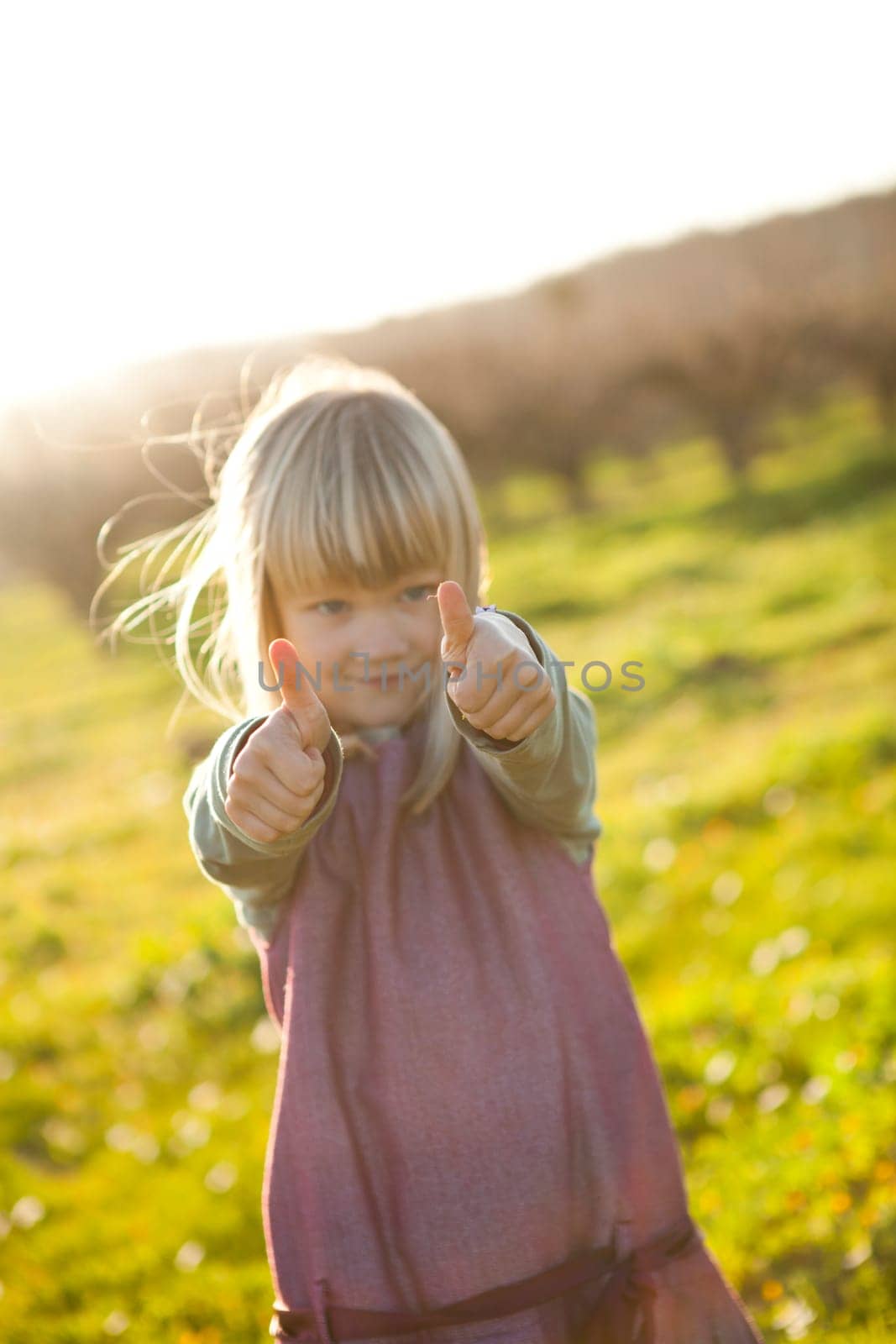 Cute little girl outdoors with thumbs up