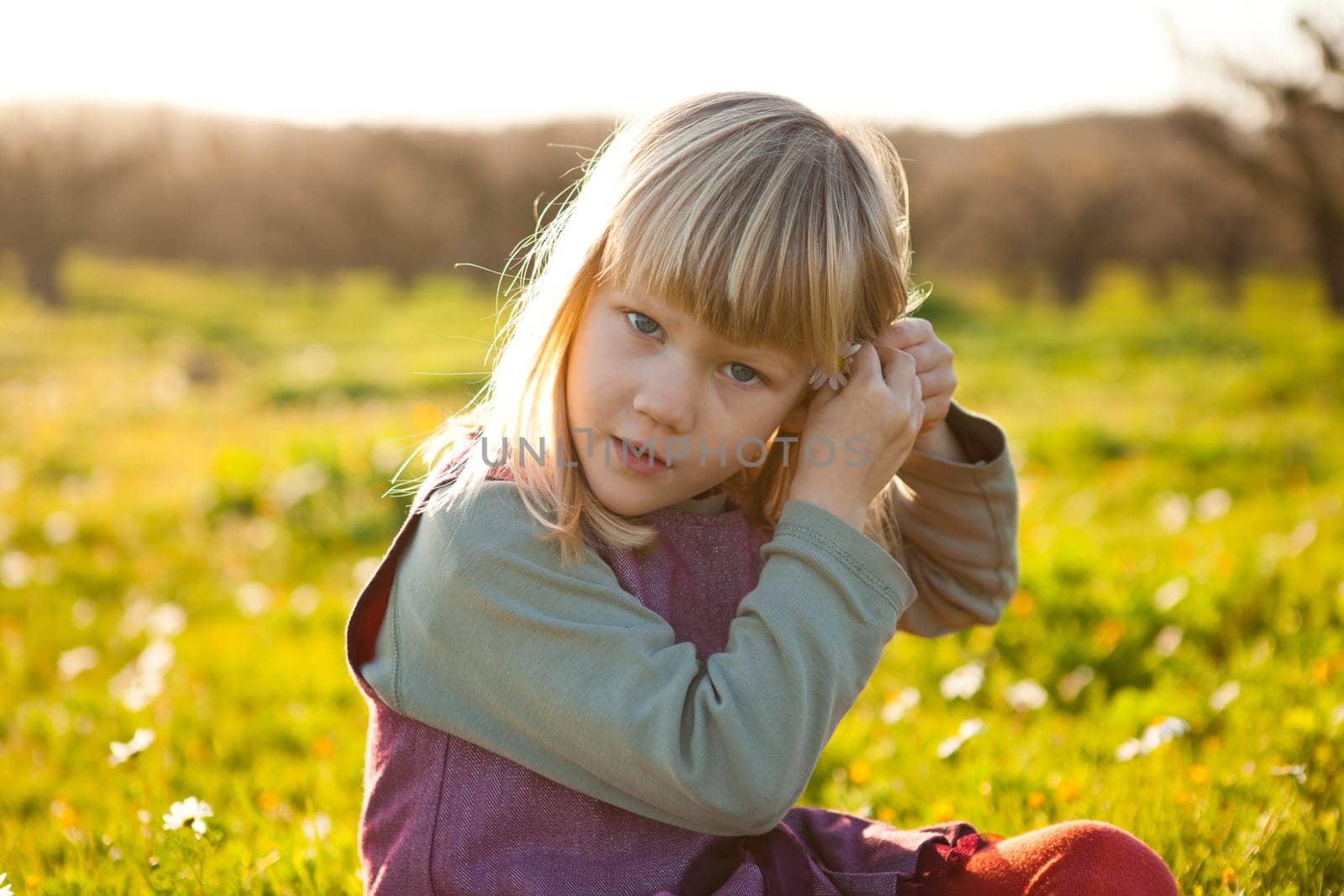 Cute little girl outdoors on a green field with flower in her hair
