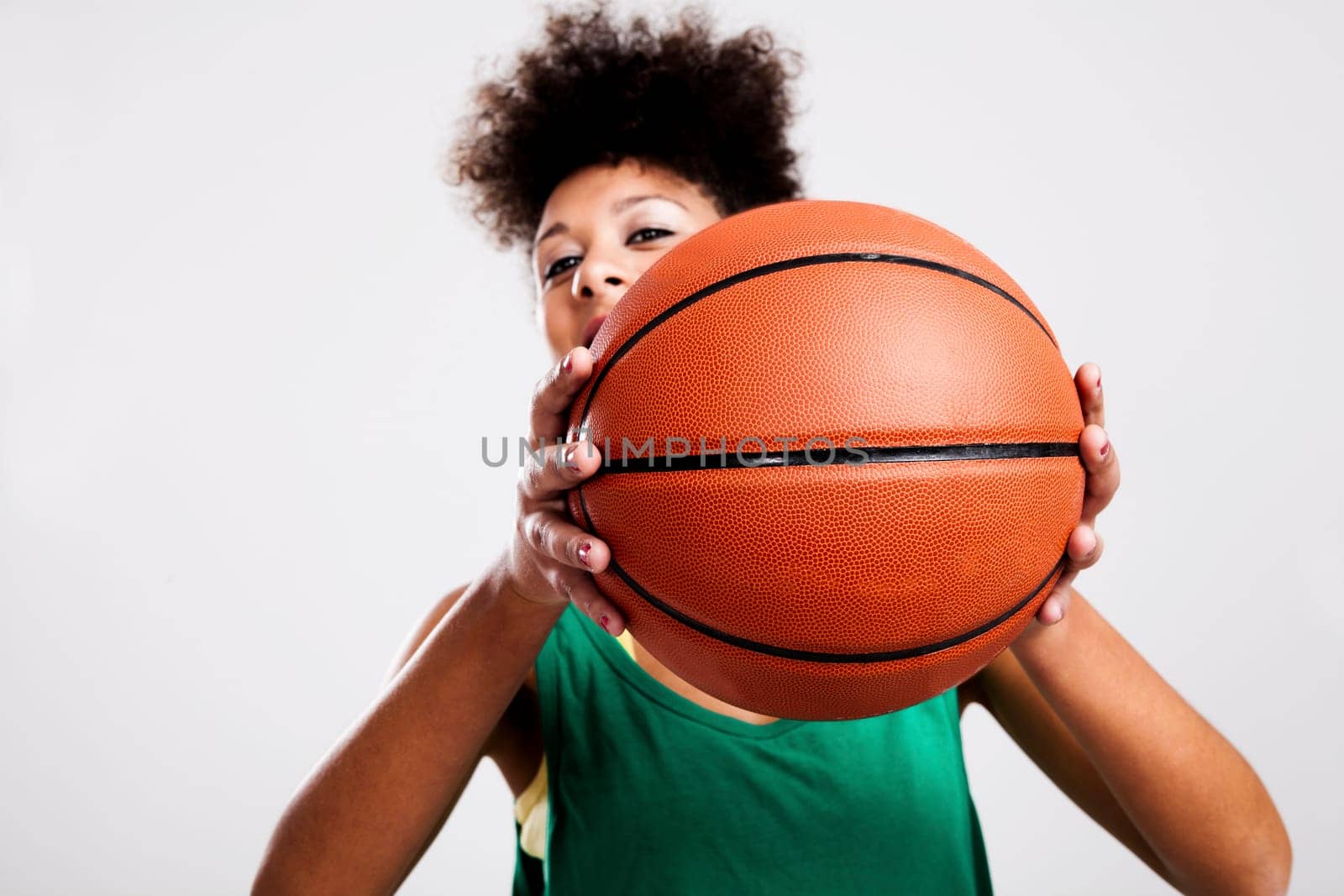 Athletic woman with a basketball in front of her face. Studio shot.