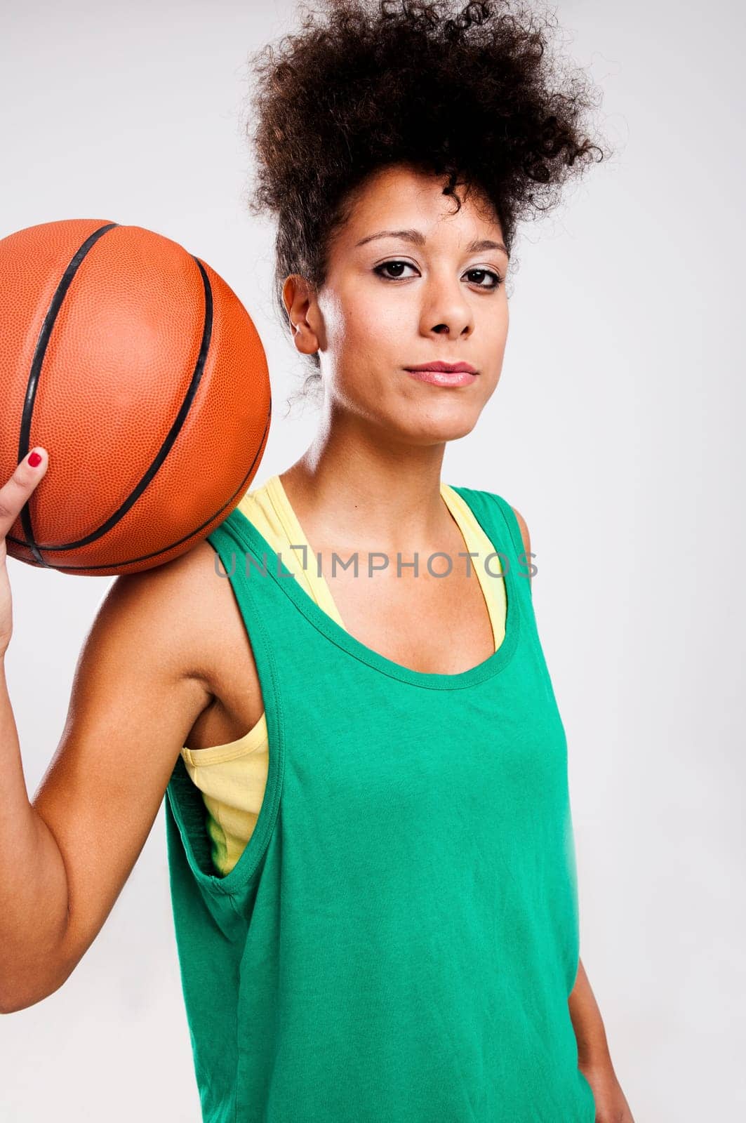 Athletic woman with a basketball on her shoulder. Studio shot.