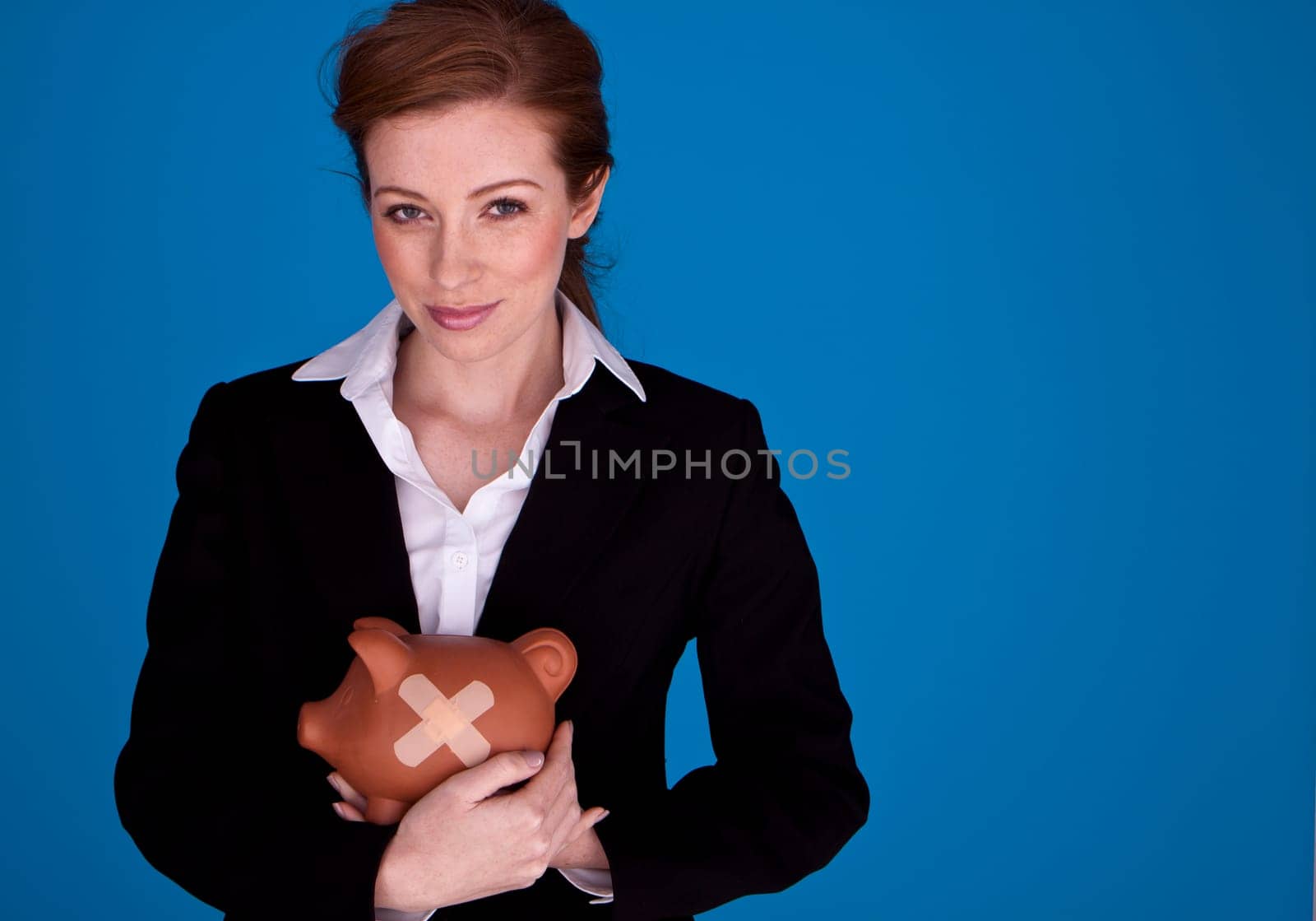 Young attractive businesswoman holding a piggybank with plasters on it as a money recovery concept.