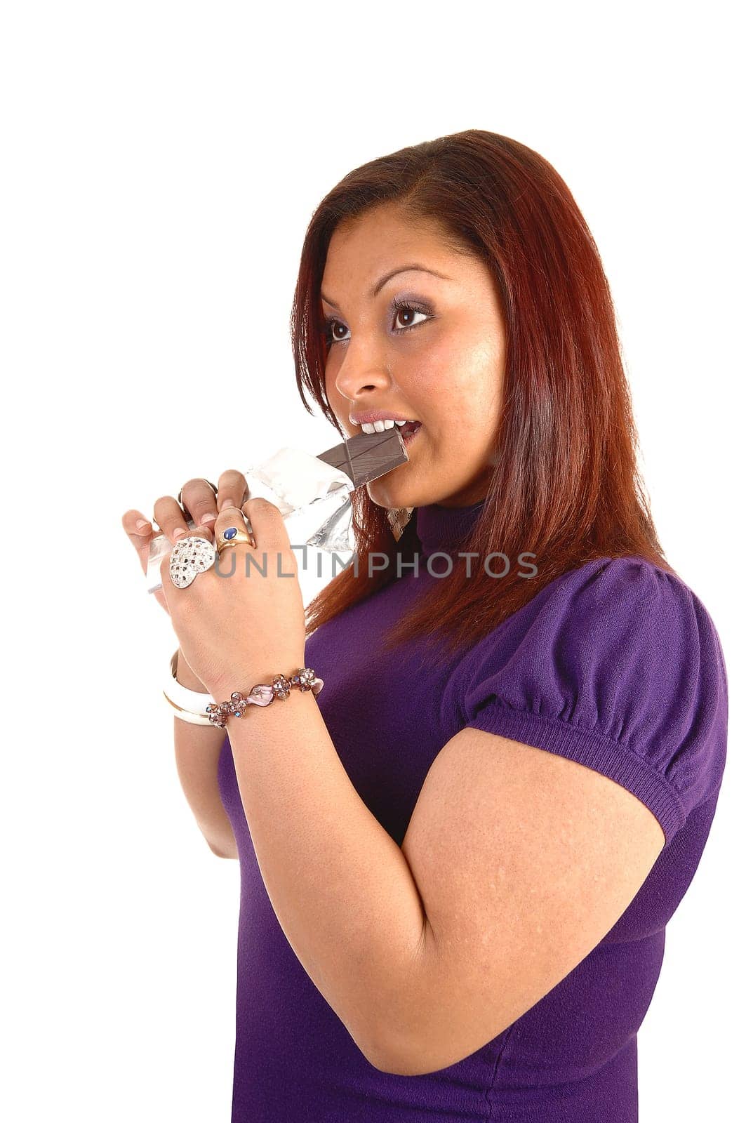 Closeup of a young woman in an purple dress eating a hole chocolate bare, with red hair for white background.