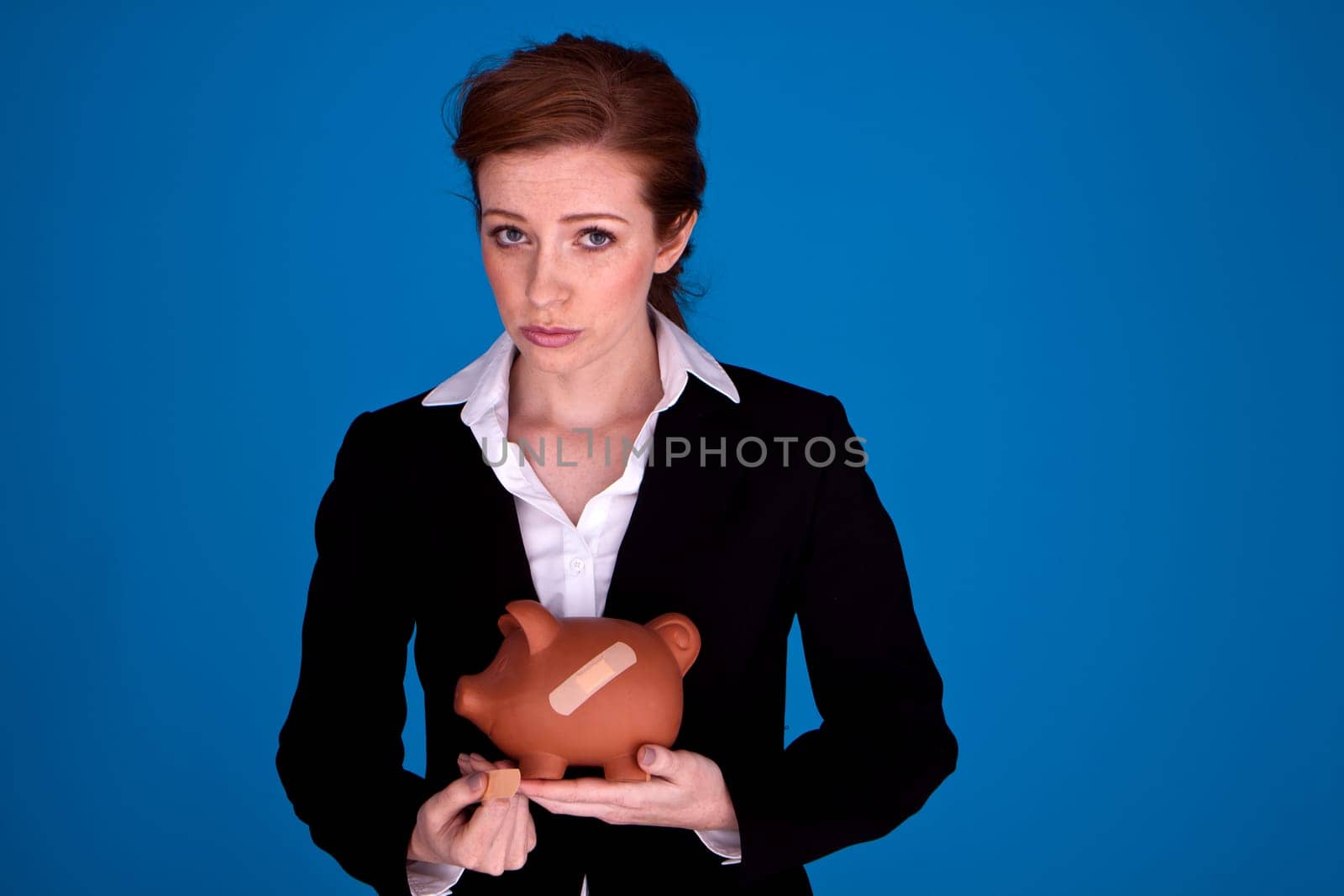 Young attractive businesswoman holding a piggybank with plasters on it as a money recovery concept.