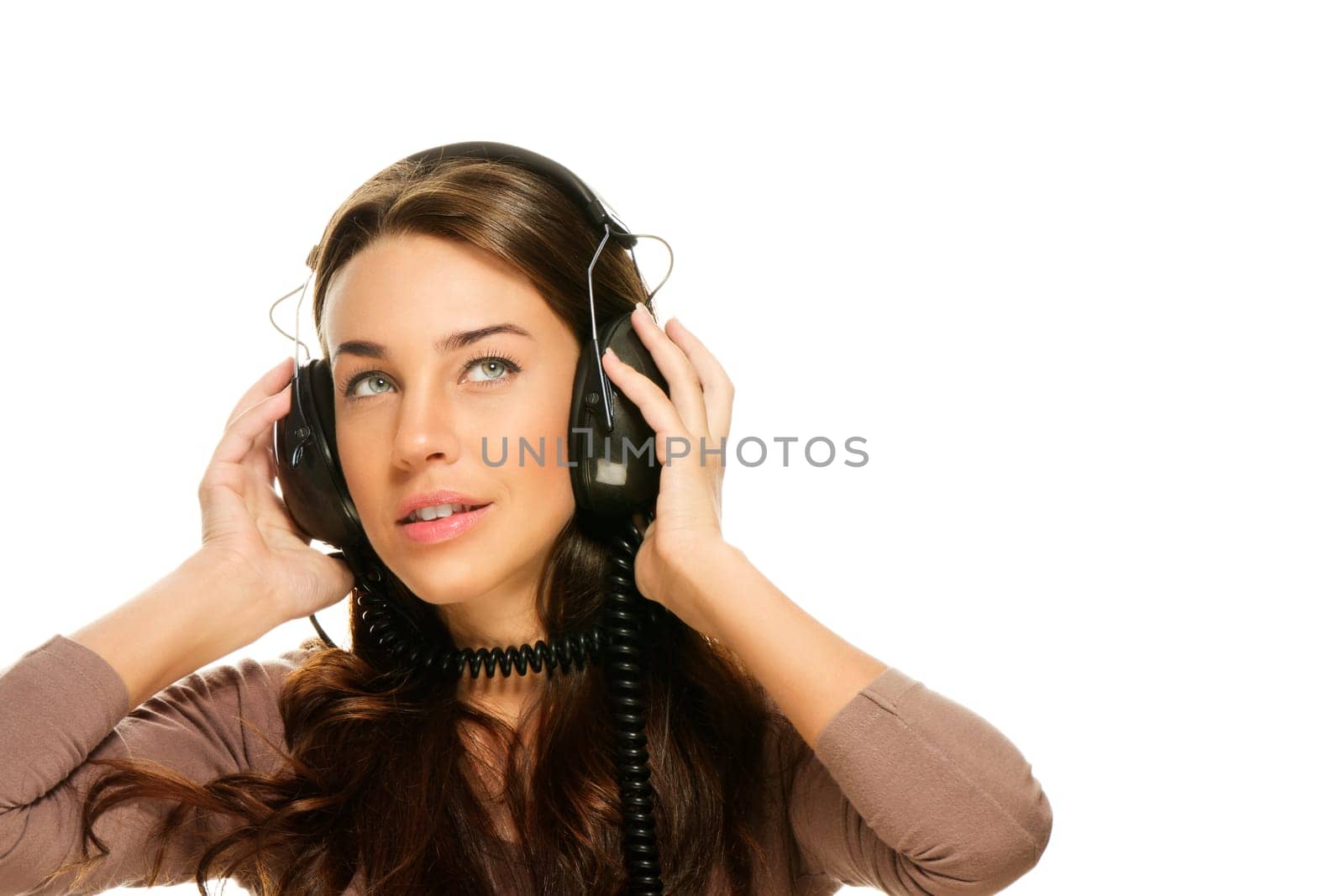 Young woman listening to music and looking up on white background