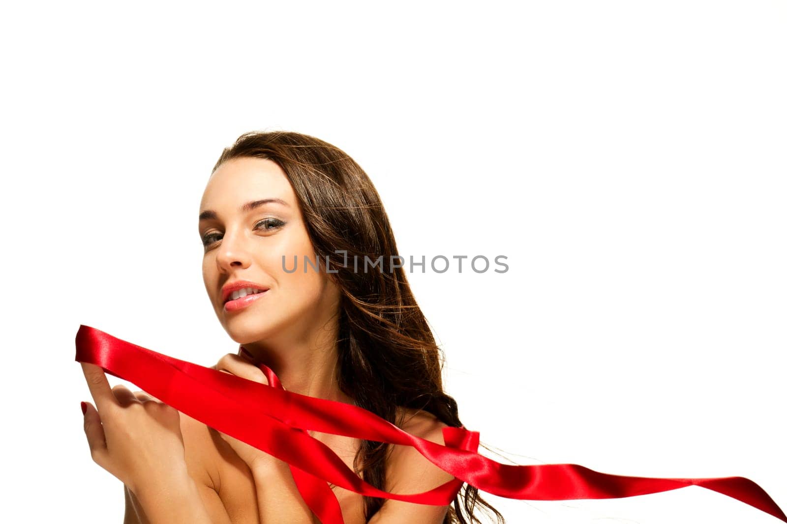 Young woman holding red ribbon with finger on white background