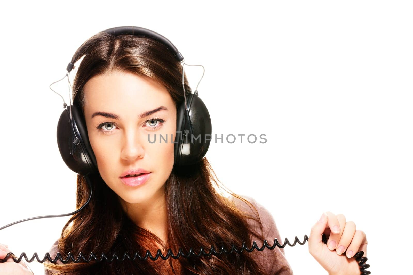 Young woman listening to music and holding cables on white background