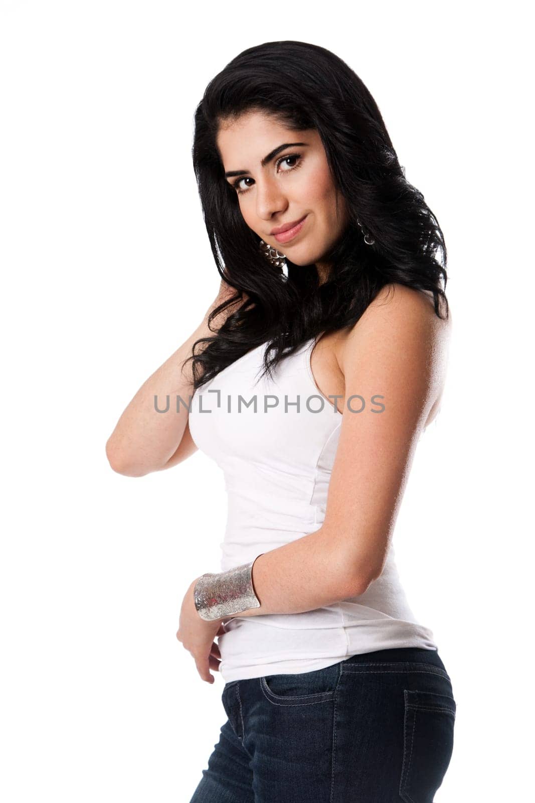 Beautiful happy smiling young woman in white shirt and blue jeans with hand in hair, isolated.