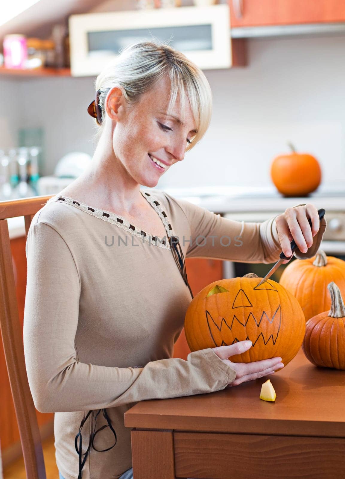 Young woman carving halloween pumpkin close up