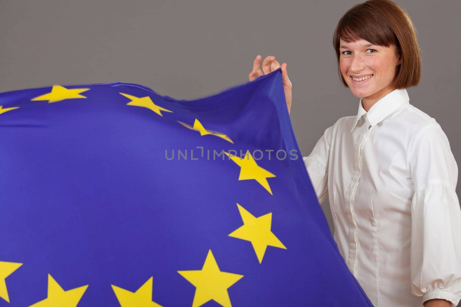 happy woman holding european flag over grey background