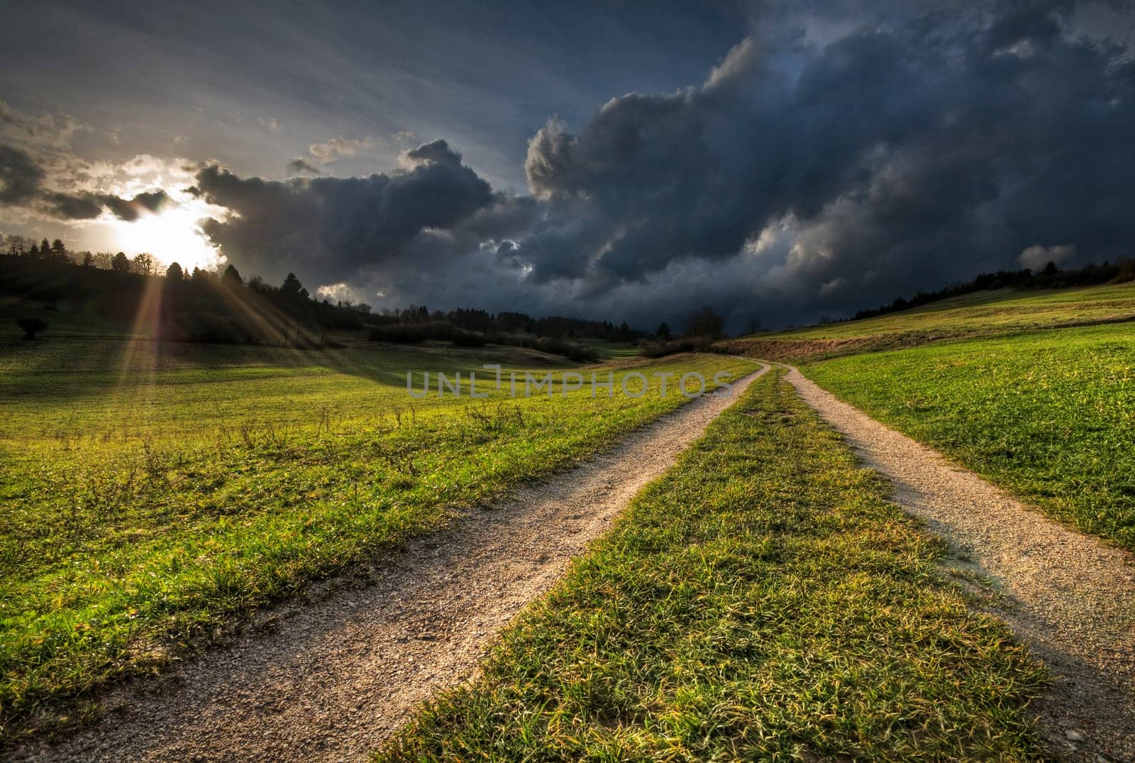 Country Road with sun shining through Rainy Clouds