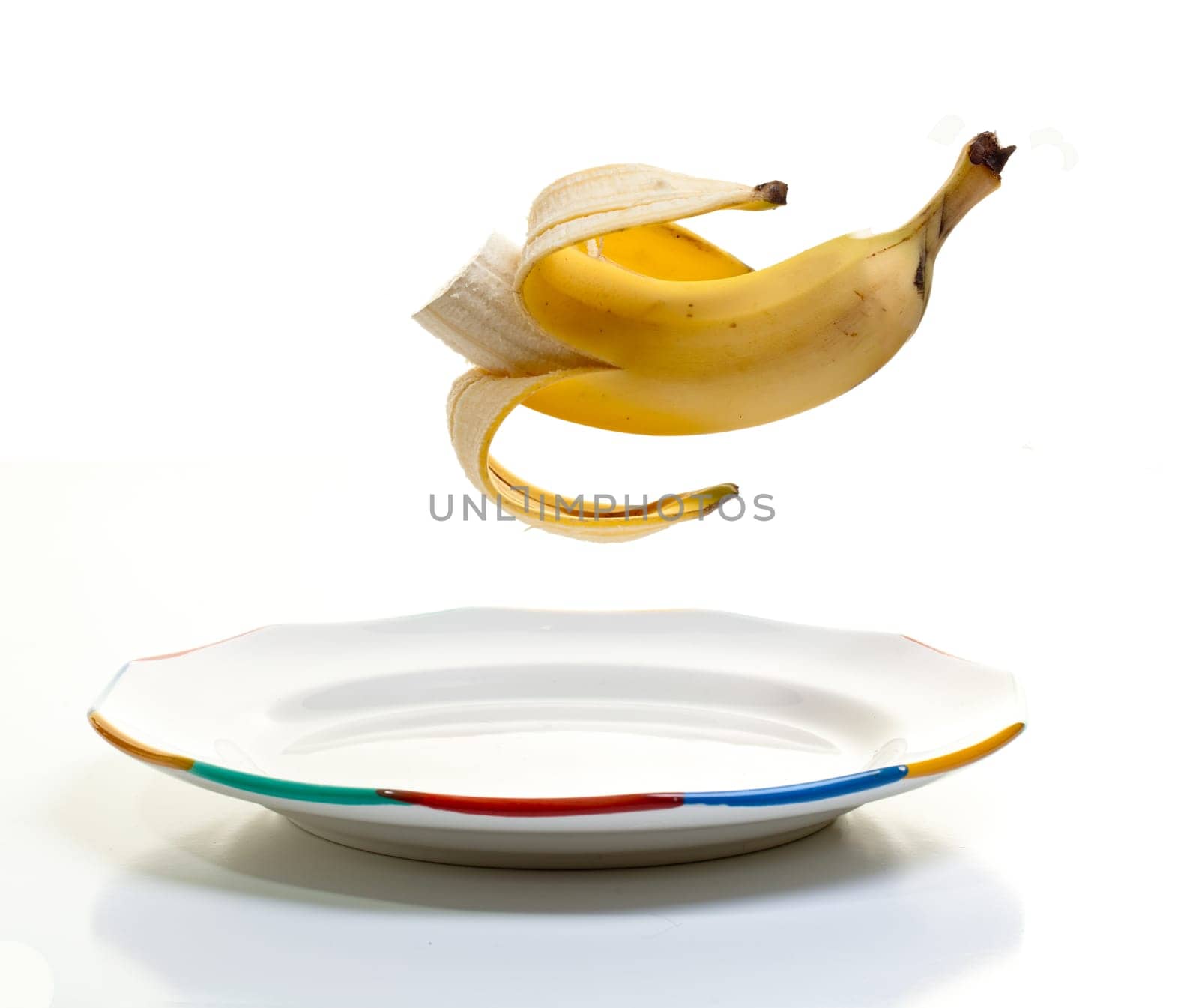 A peeled banana suspended midair over a plate