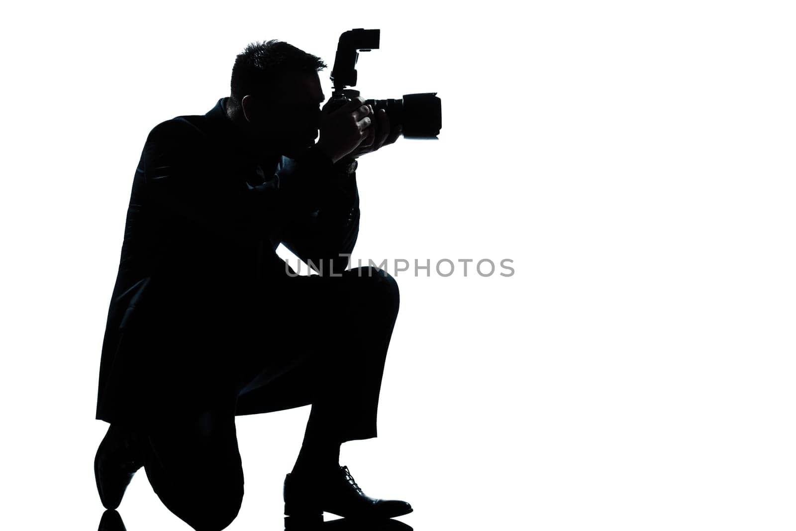one caucasian man kneeling photographer full length silhouette in studio isolated on white background