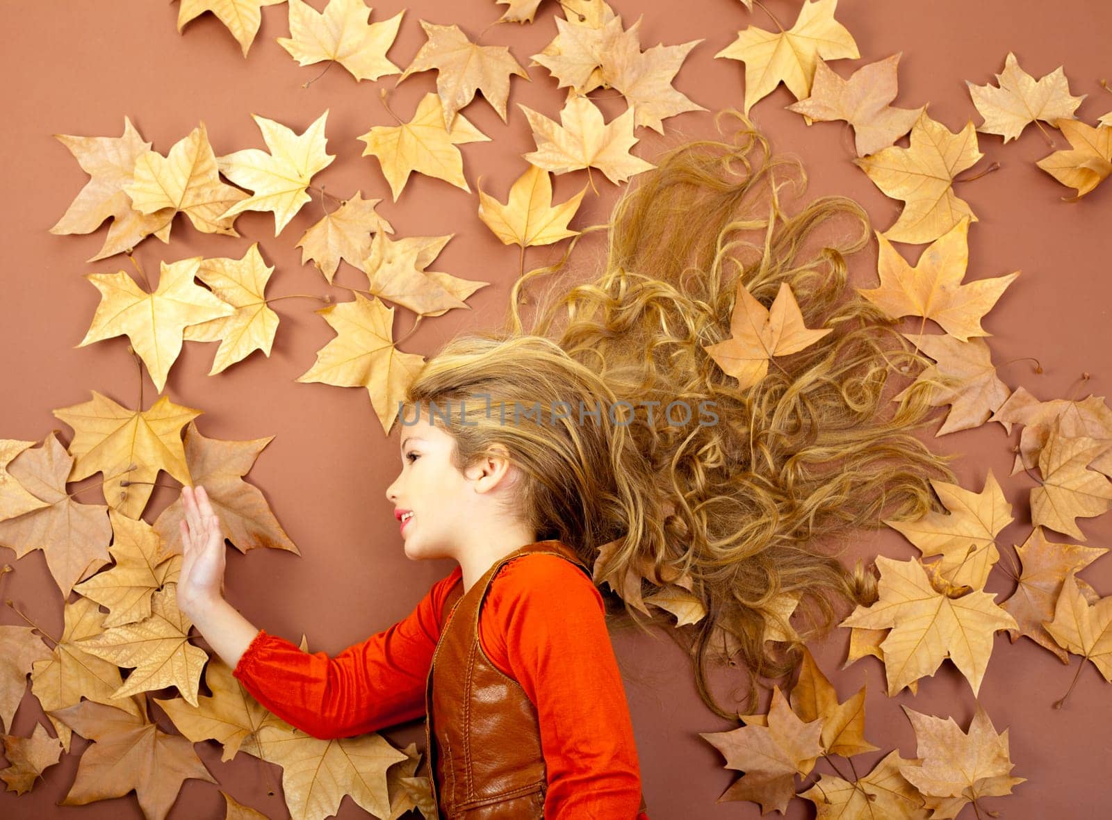 autumn fall little blond girl on dried tree leaves