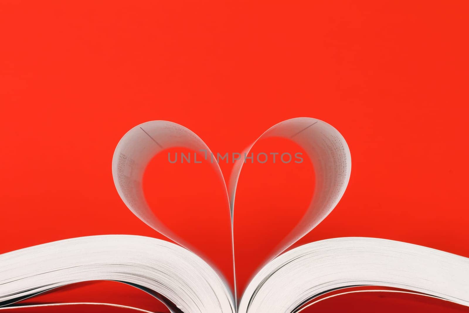 book with pages in heart shape over red background