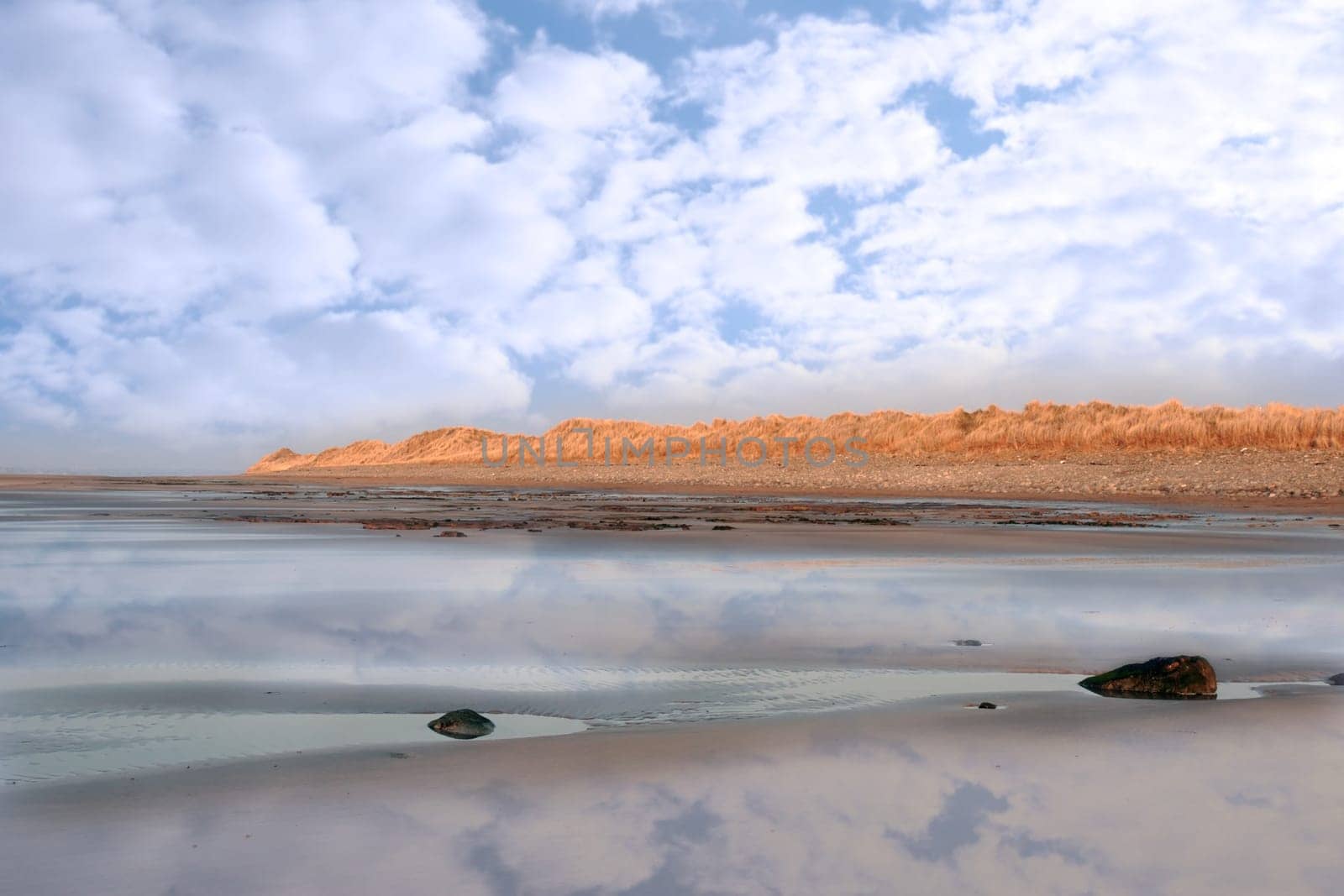 golden sand dunes on an irish beach reflected on deserted beach