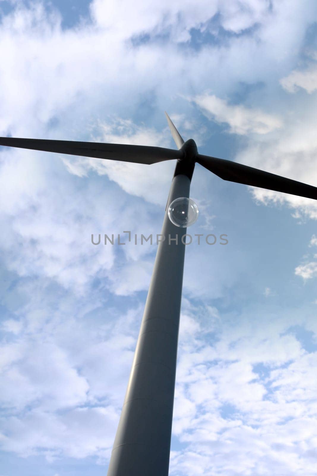 a wind turbine against a calm cloudy sky with a bubble floating