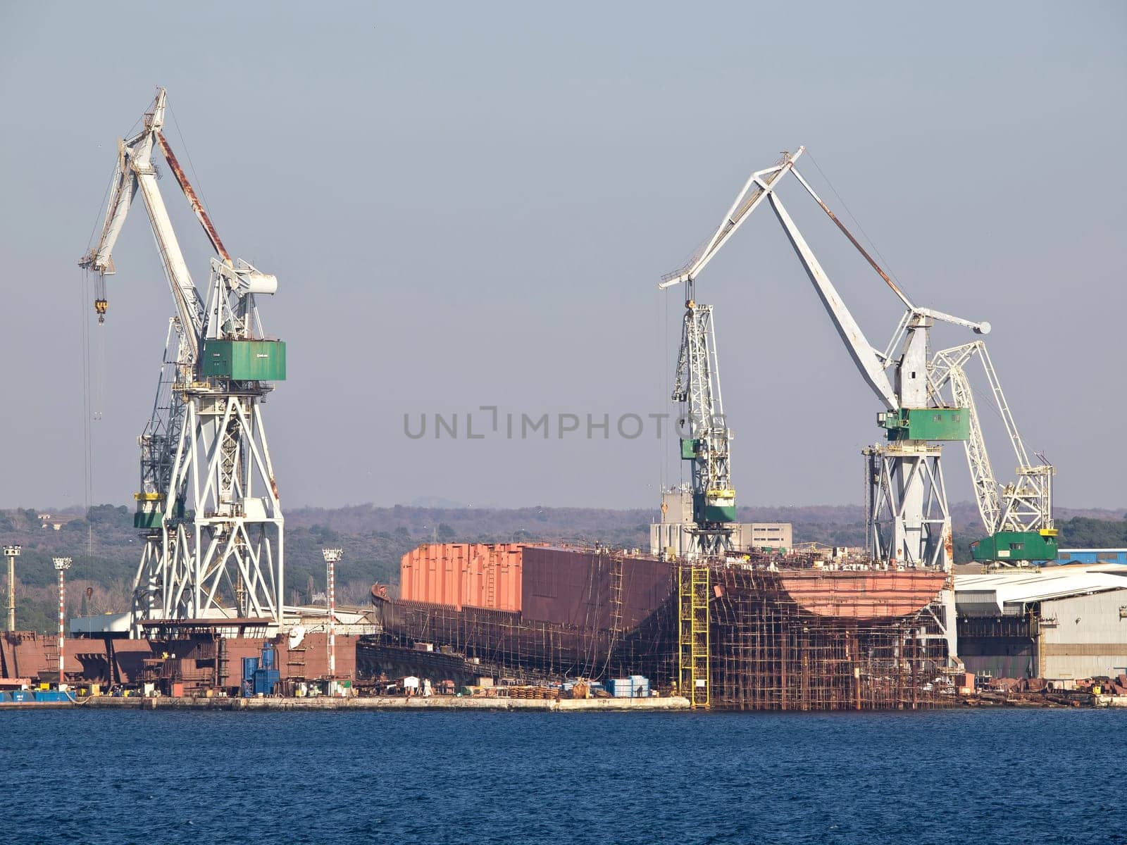 shipyard with docks and crane and blue sea