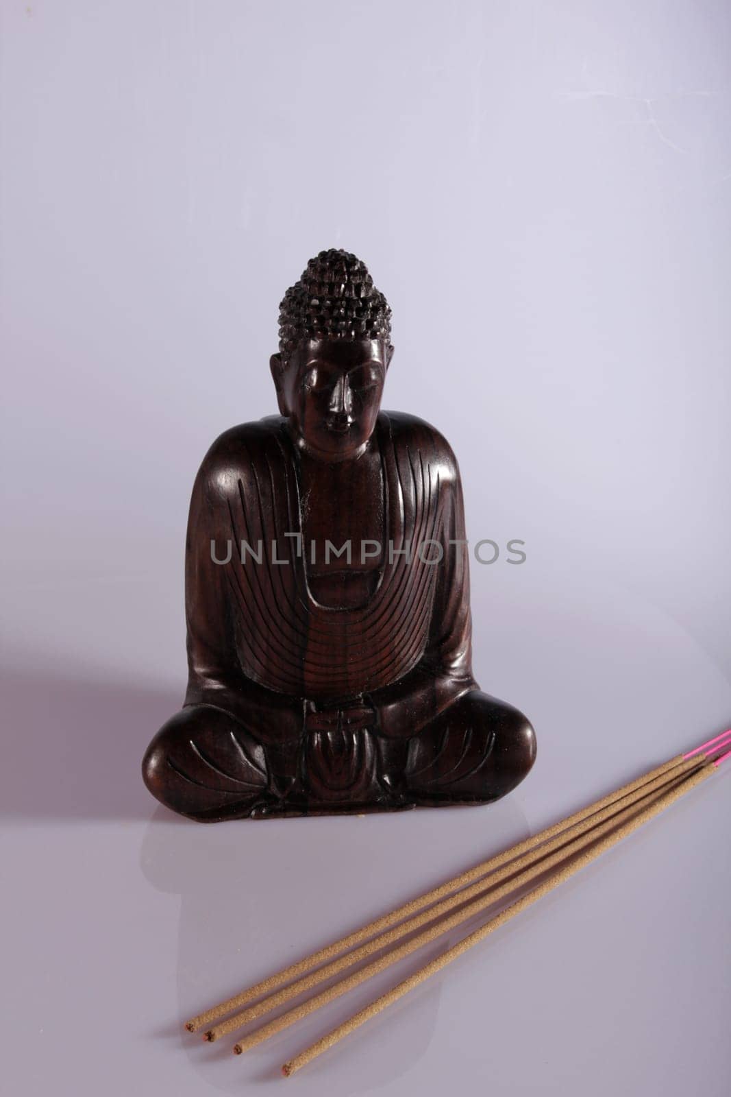 Wooden Buddha meditating with incense