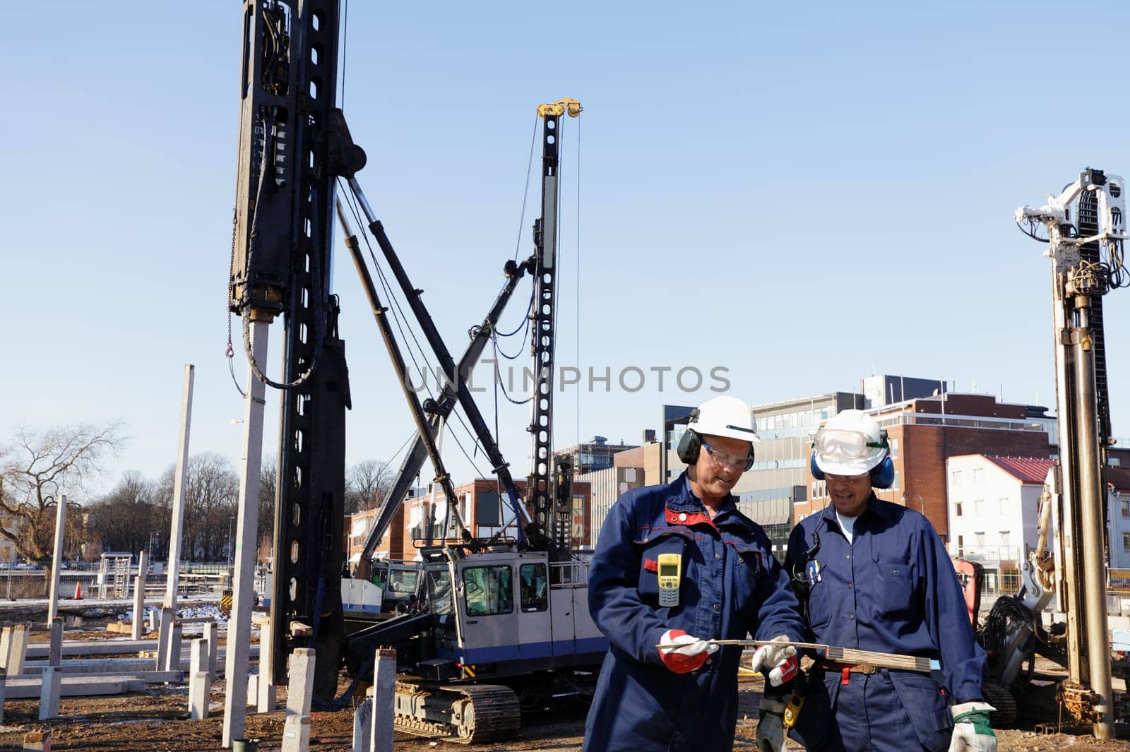 construction workers, engineers working inside building-site, machinery in background