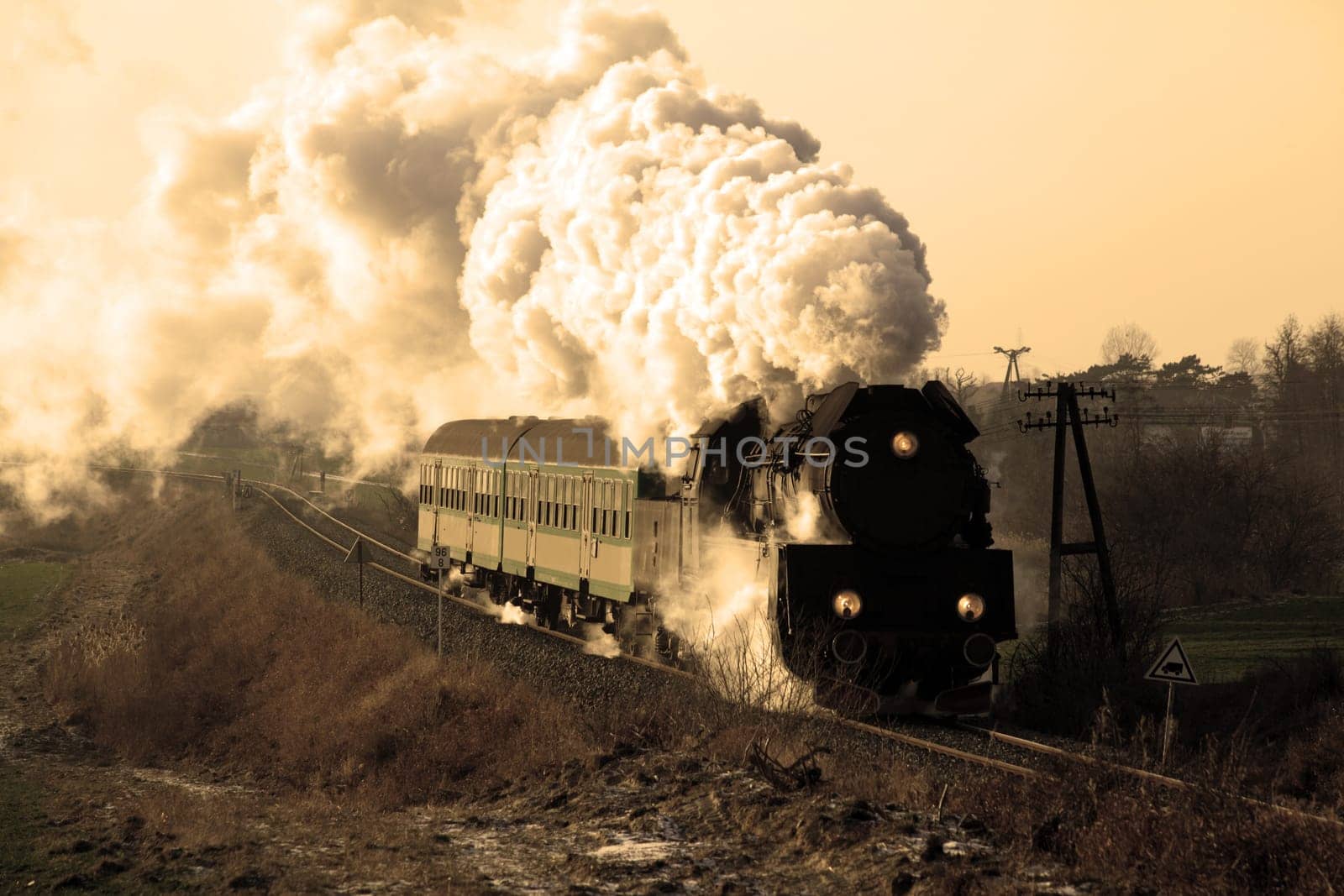 Vintage steam train passing through countryside, wintertime