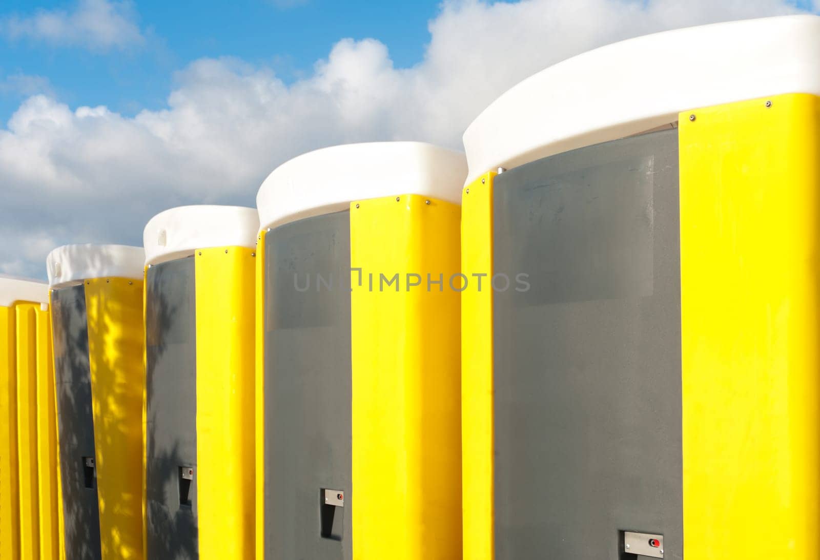yellow portable toilets under a nice cloudy sky