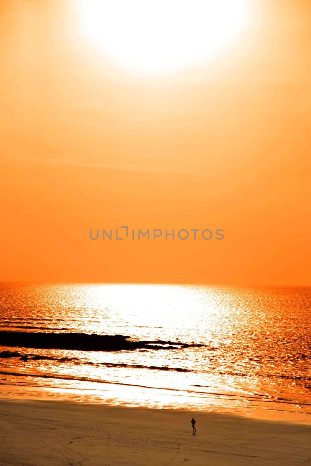 sunshine reflected on a golden beach with jogger of the west coast of ireland