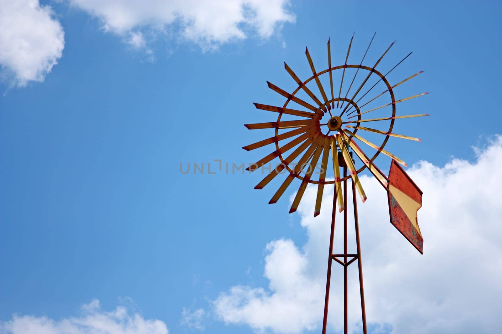 Vintage farm windmill against blue sky