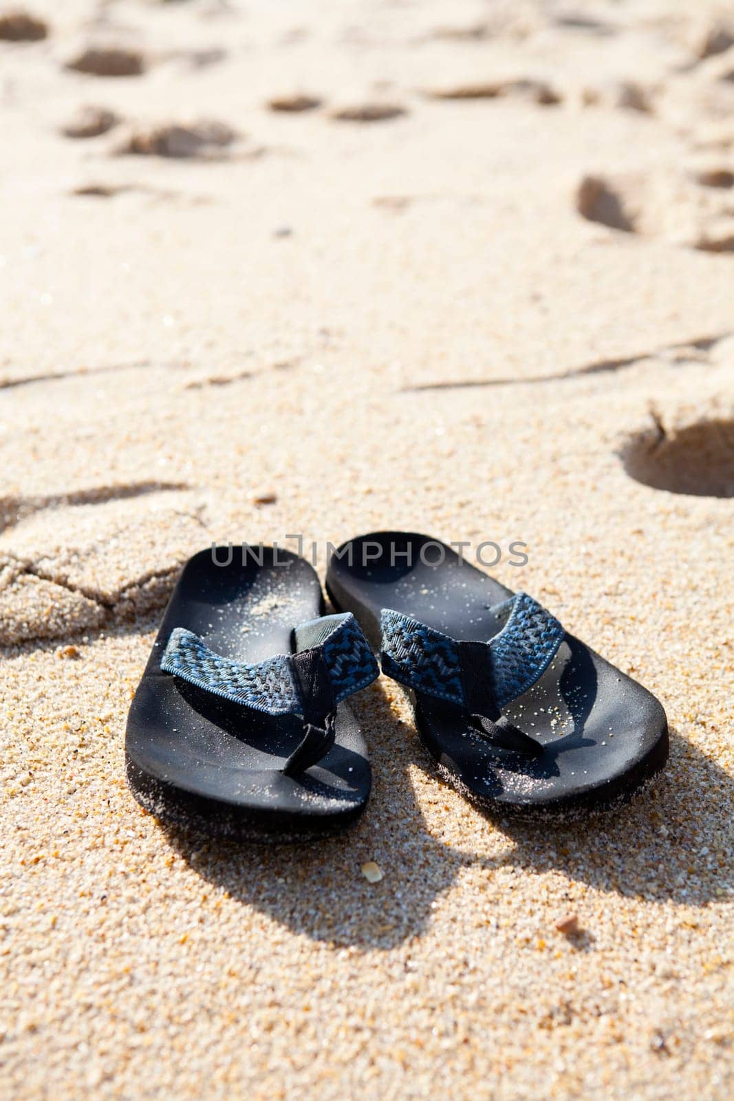 Close-up of flip flops in sand on the beach
