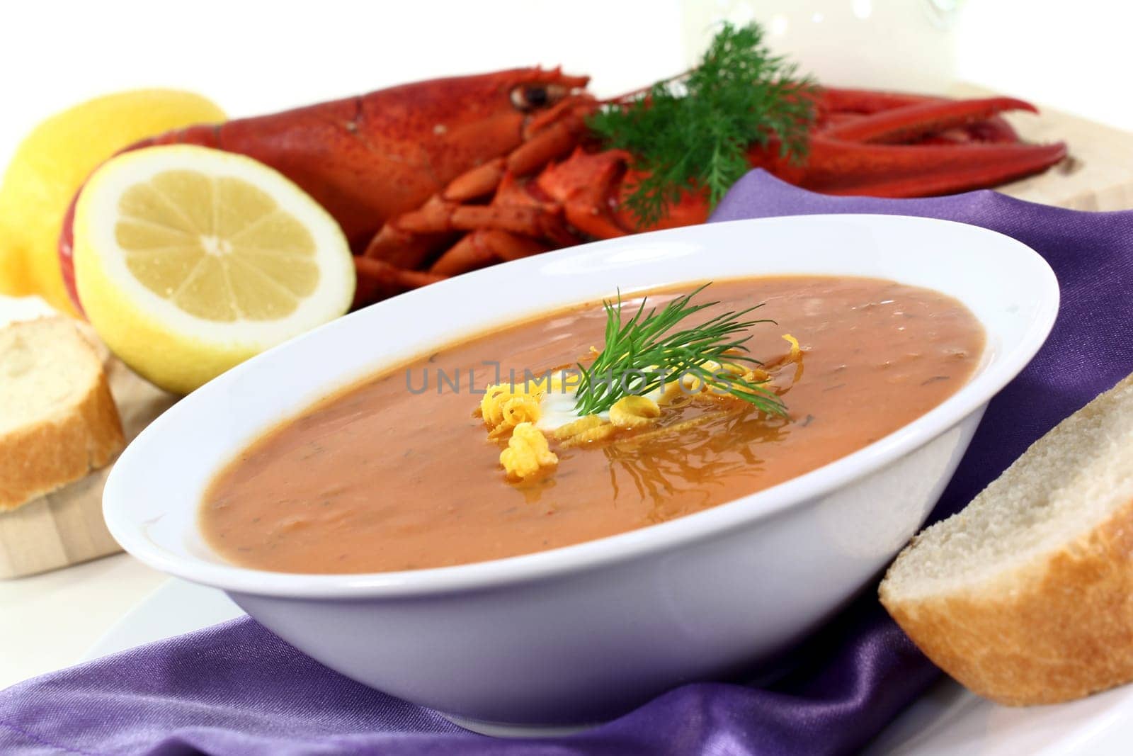 a bowl of lobster cream soup with dill and lemon