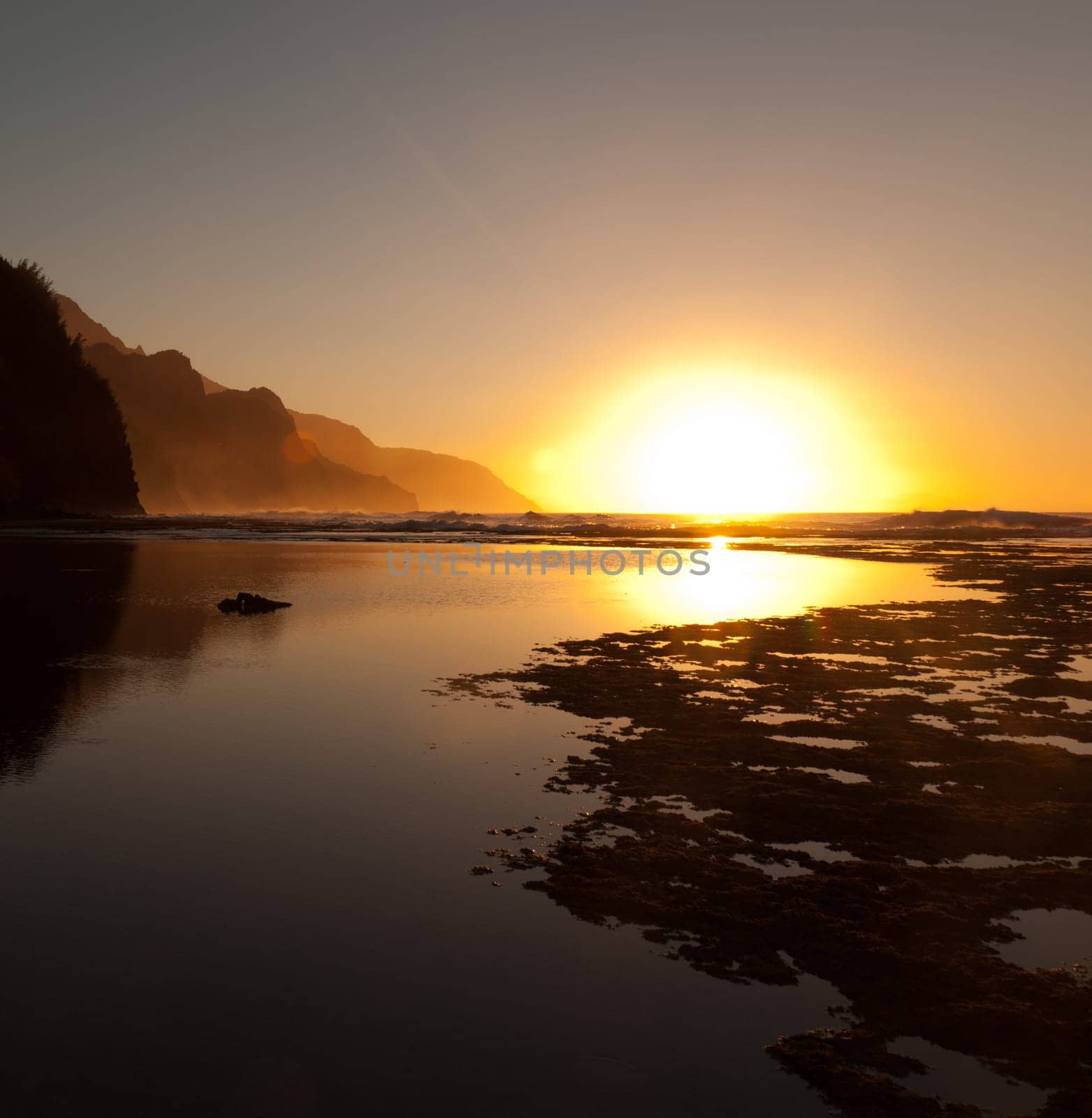 Reflections of setting sun over Na Pali coast by Ke&#039 e beach in Kauai at sunset