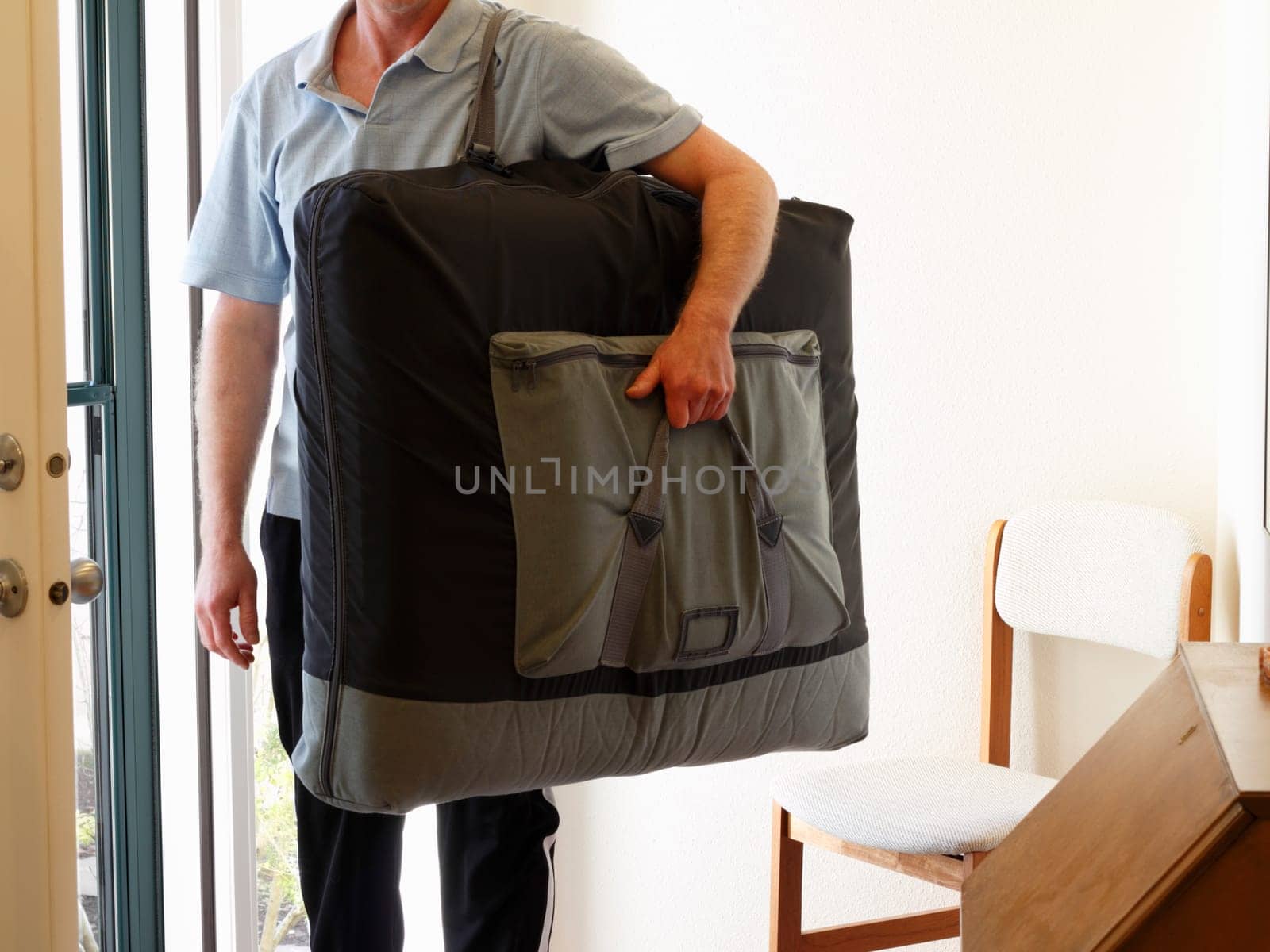 Massage therapist standing inside front door of home ready to give a client a massage at their home.