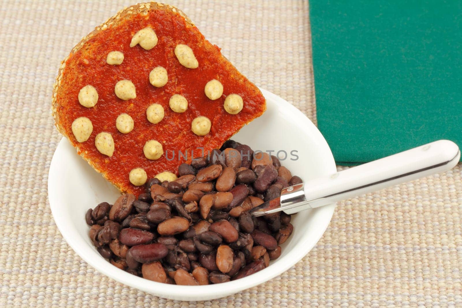 Vegetarian breakfast of dark red kidney, black and pinto beans with sprouted grain bread toast topped with tomato paste and horseradish mustard.