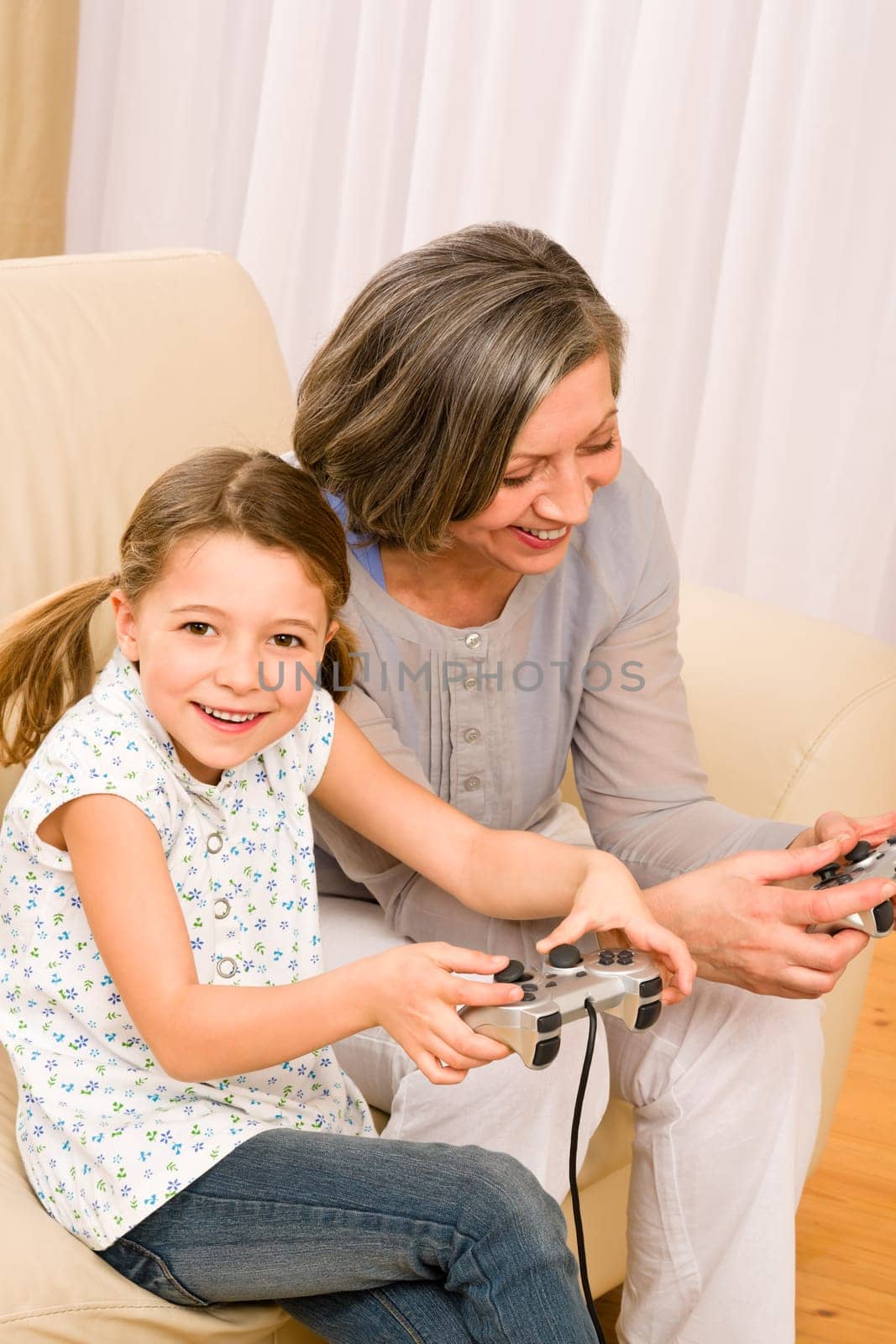 Grandmother play computer game with enthusiastic young girl have fun smiling