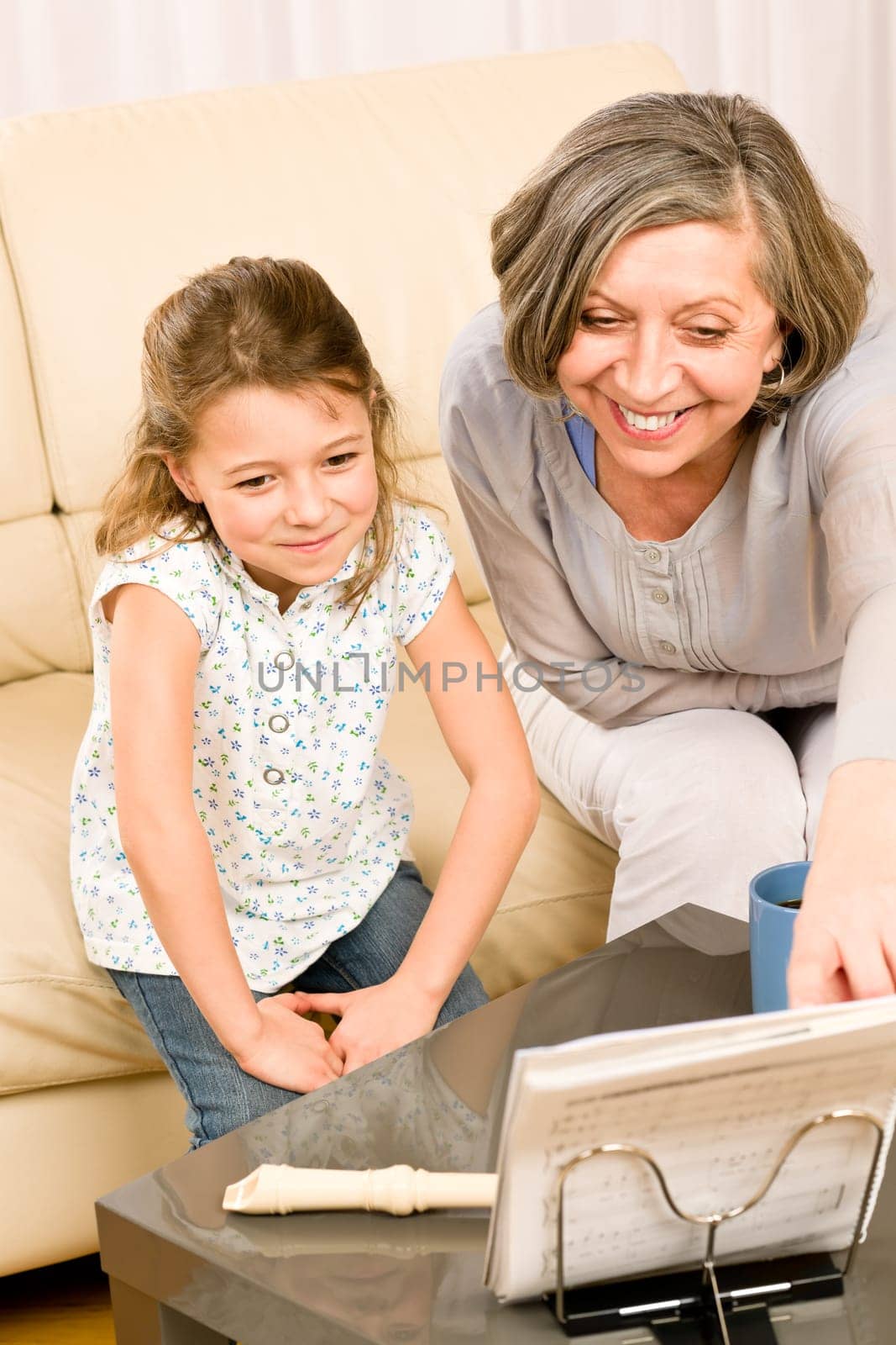 Grandmother teach young girl learn music notes play flute smiling