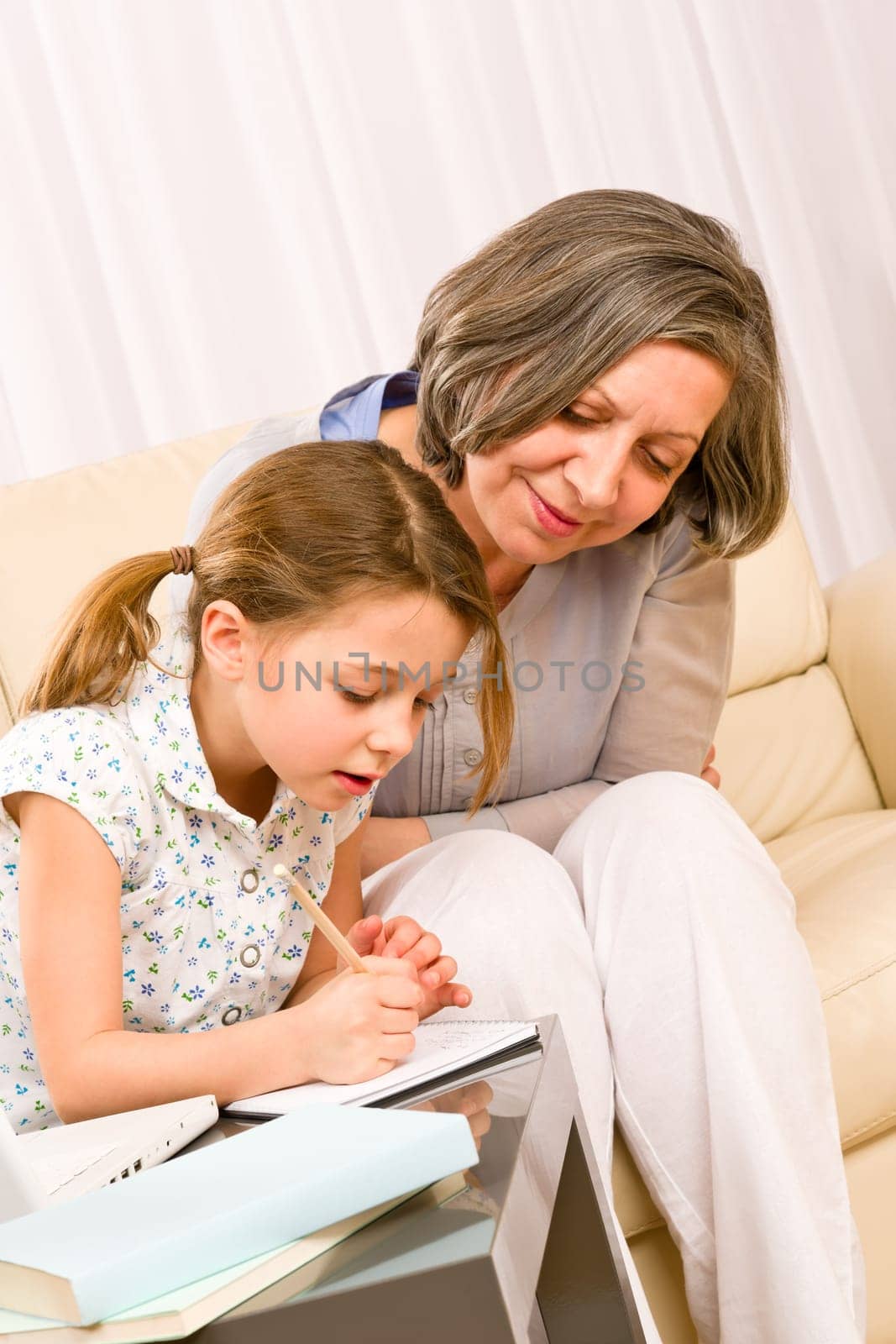 Grandmother help granddaughter doing school homework together at home