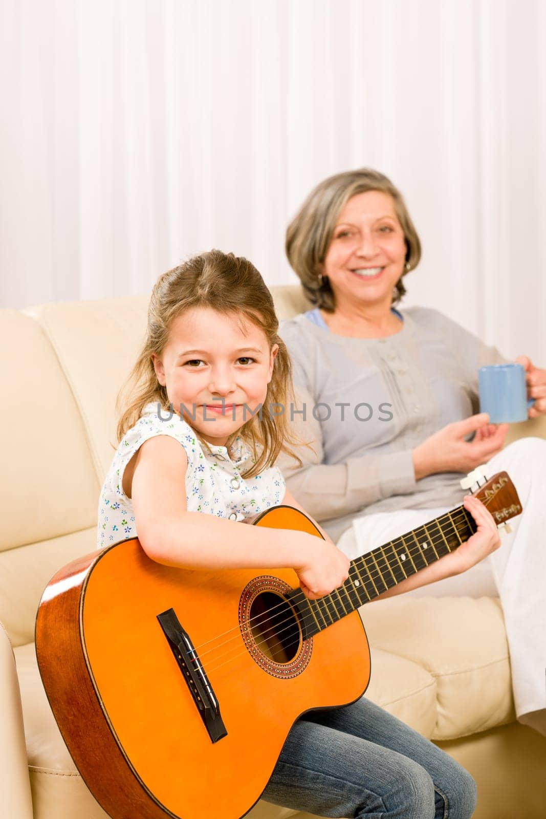 Young girl granddaughter sing play guitar to grandmother smile