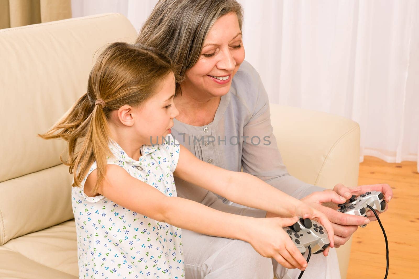 Grandmother play computer game with enthusiastic young girl have fun smiling
