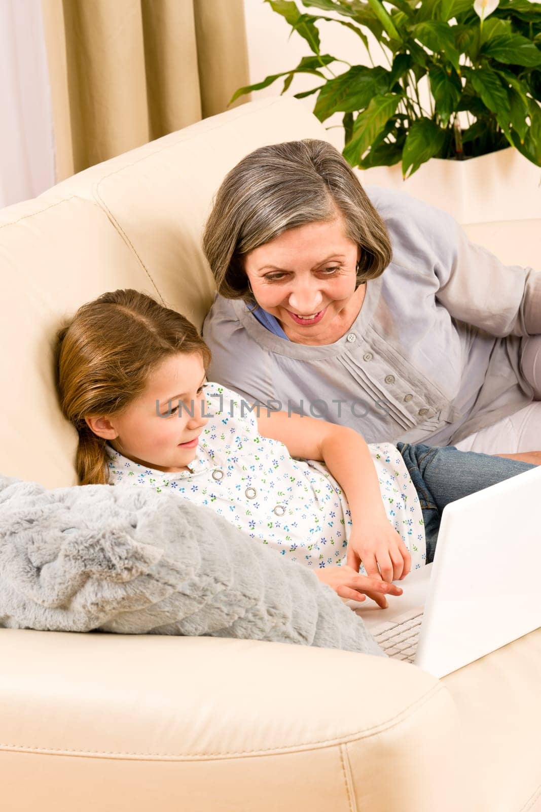 Grandmother with young girl use computer laptop happy together