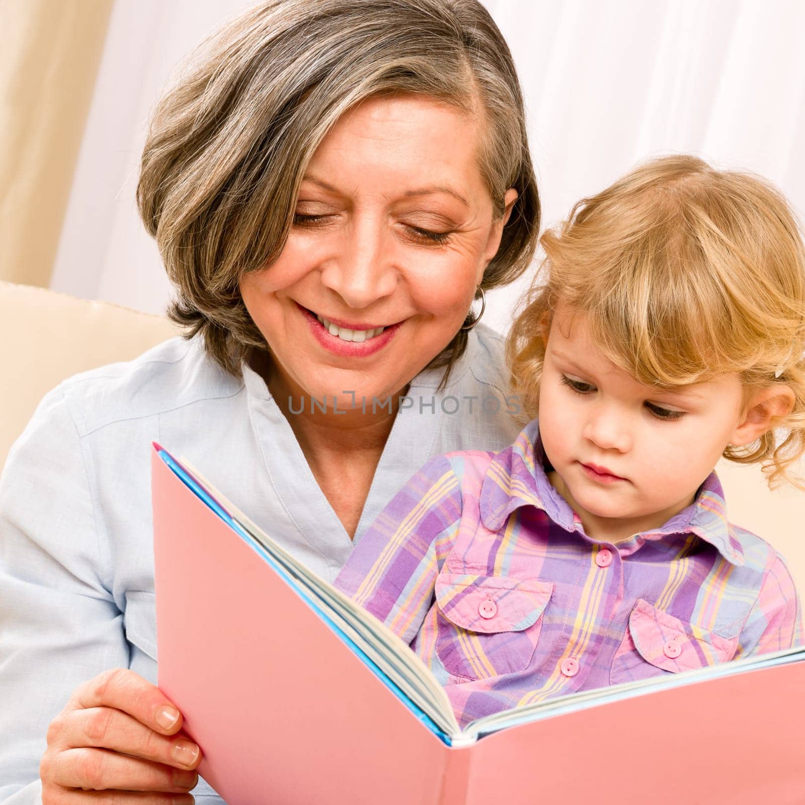 Grandmother and little girl reading book happy together at home