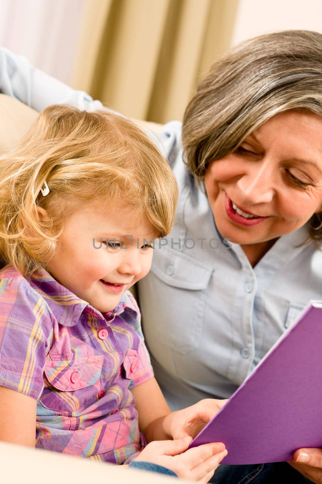 Grandmother and little girl reading book happy together at home