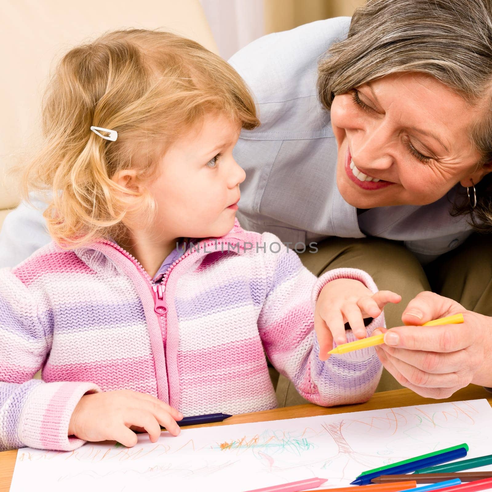 Grandmother and granddaughter drawing together with pencils at home