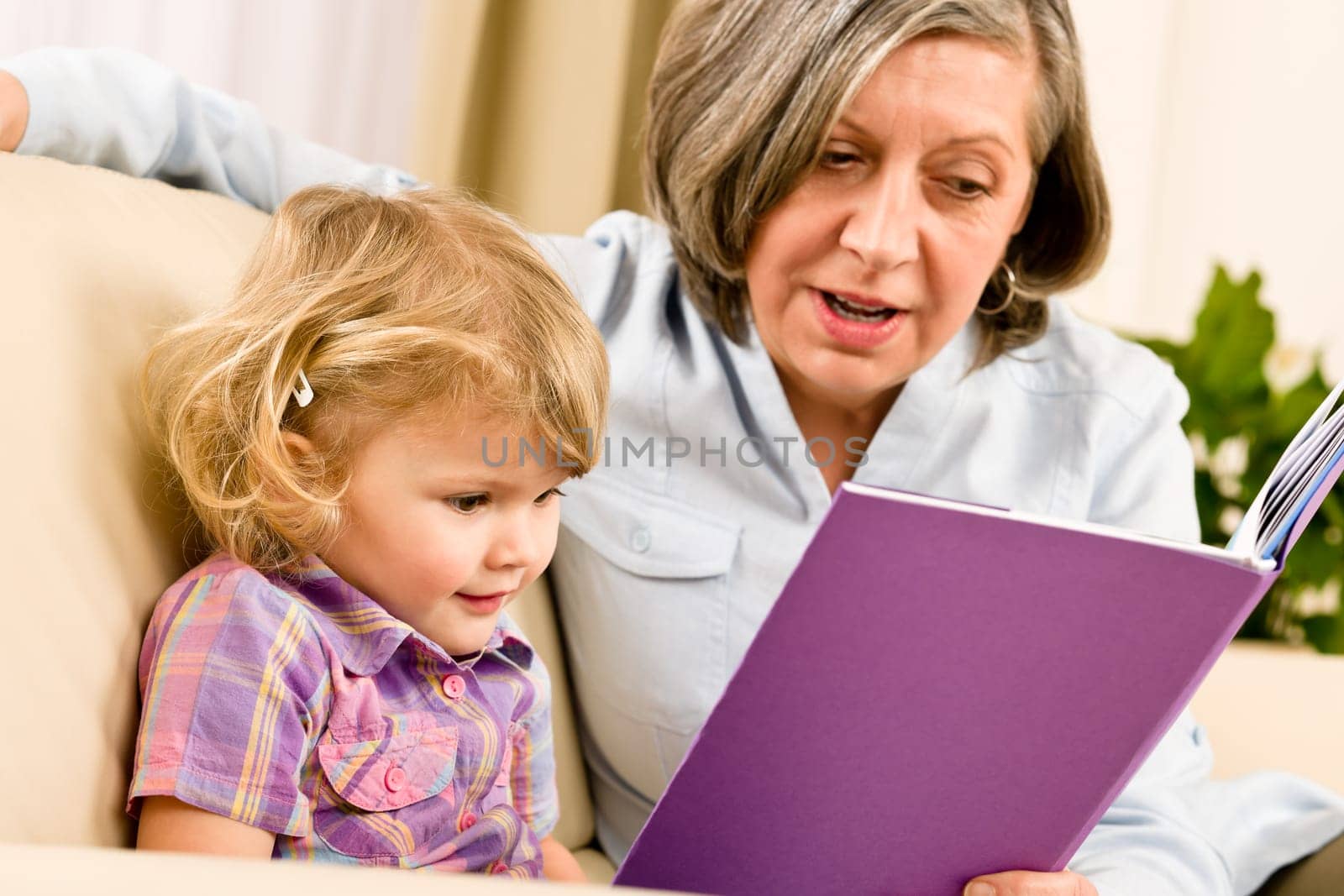 Grandmother and little girl reading book happy together at home